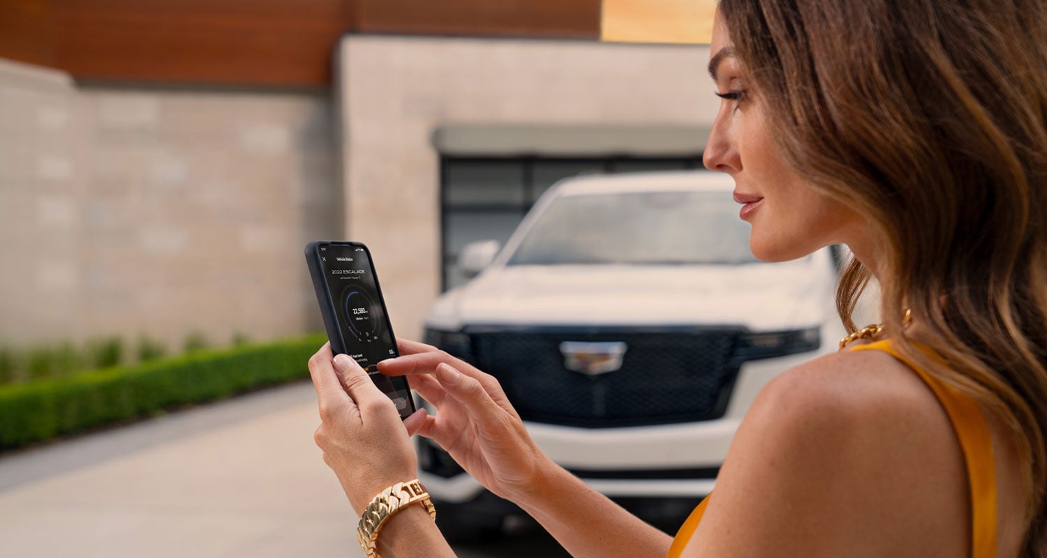 lady checking her mobile with a Cadillac vehicle background | Ross Downing Cadillac in HAMMOND LA